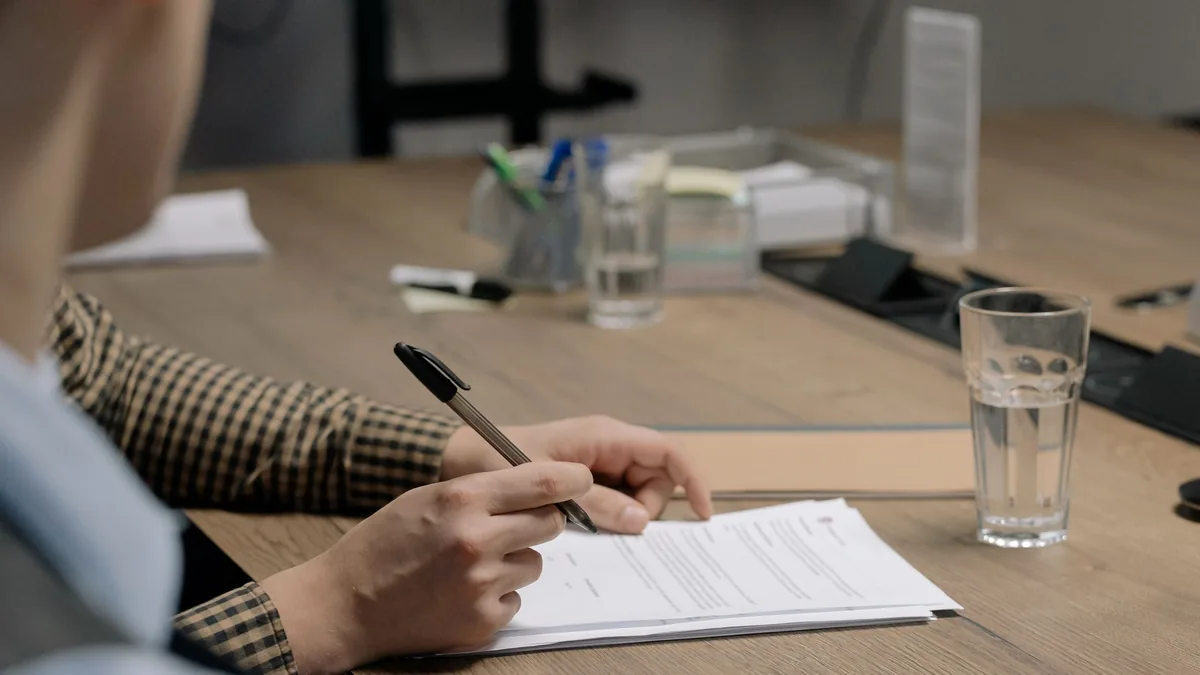 Pessoa assinando documentos sobre uma mesa