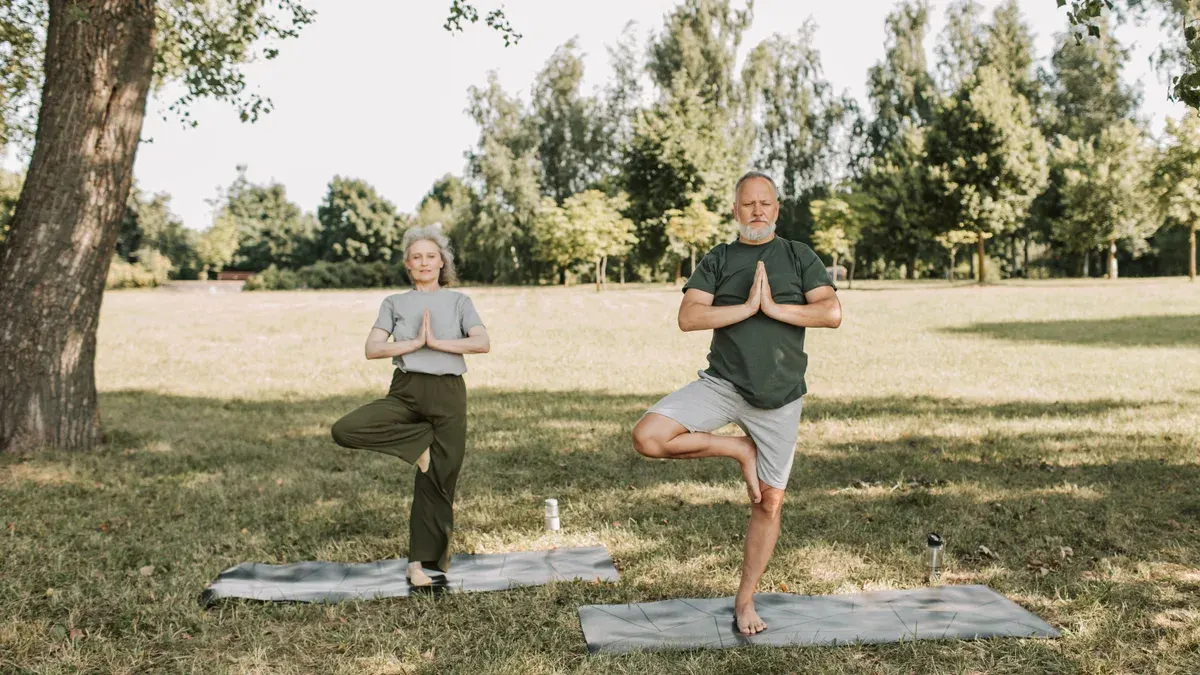 Casal sênior fazendo yoga ao ar livre em um parque