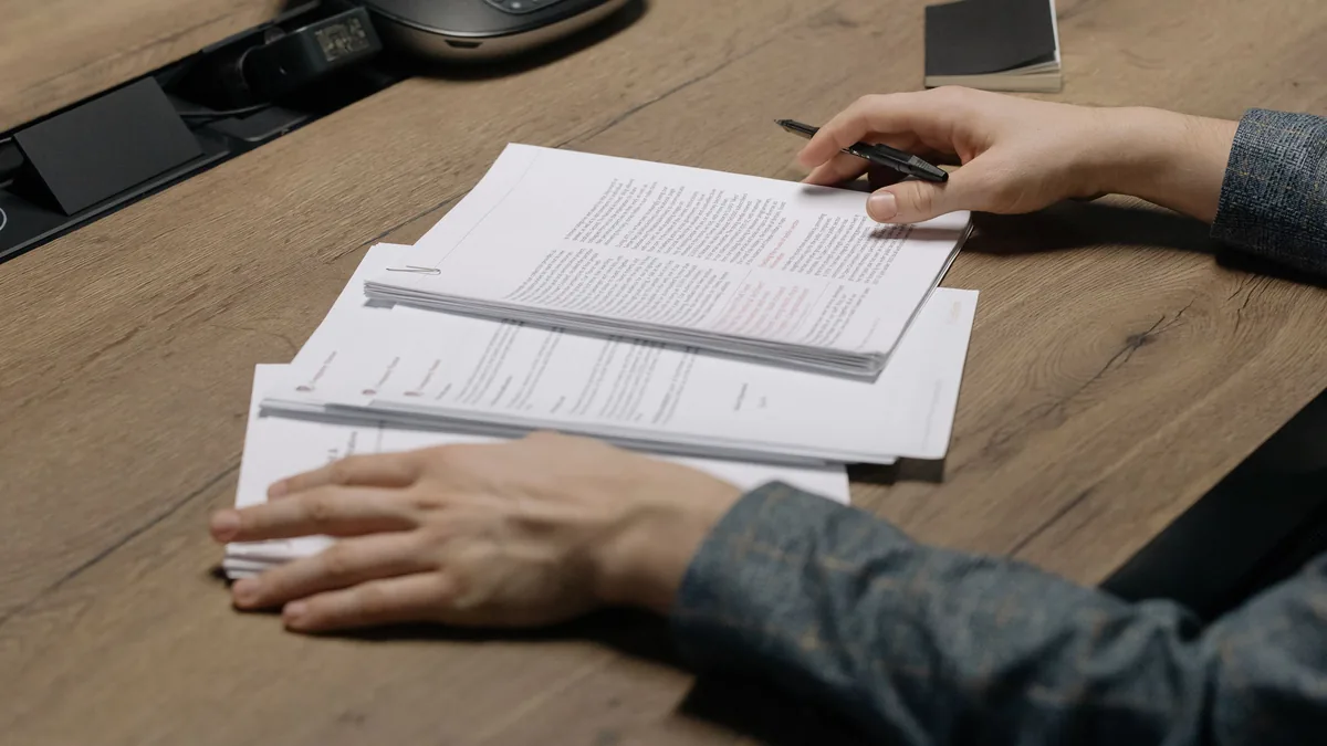 Pessoa revisando documentos com caneta em um escritório