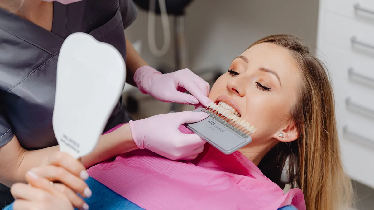 Dentista mostrando uma escala de cores dentais para um paciente
