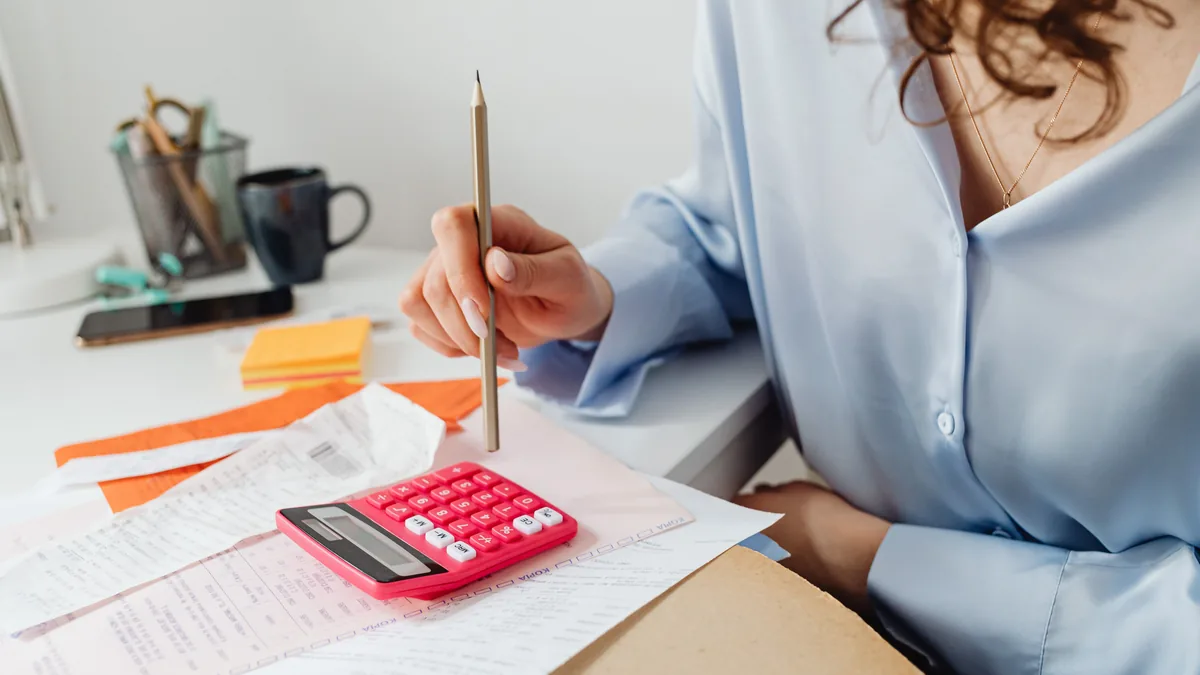 Pessoa revisando contas com calculadora sobre a mesa
